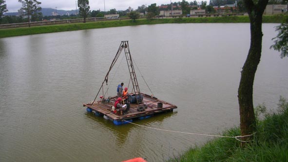 Fotografia de equipe executando sondagem à percurssão em balsa no rio
